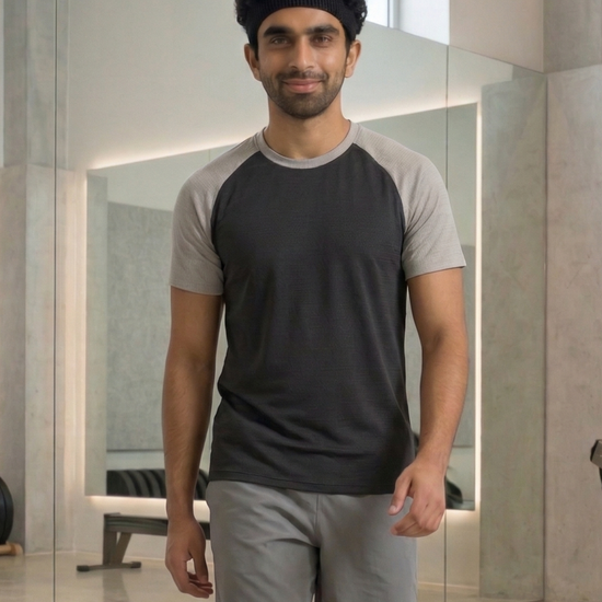Man wearing a black and gray t-shirt with gray shorts in an indoor setting.