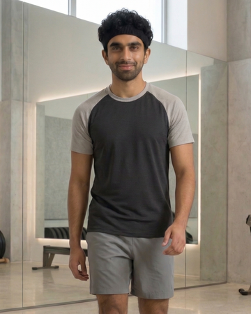 Man wearing a black and gray t-shirt with gray shorts in an indoor setting.