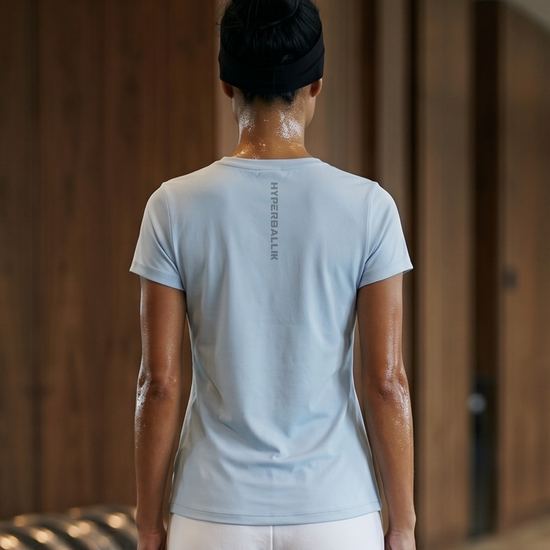 Person wearing a light blue t-shirt and white pants in a wooden interior setting