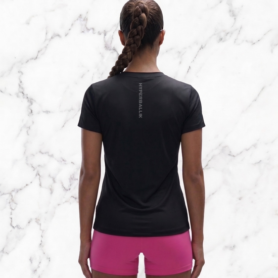 Person wearing a black t-shirt and pink shorts on a marble background