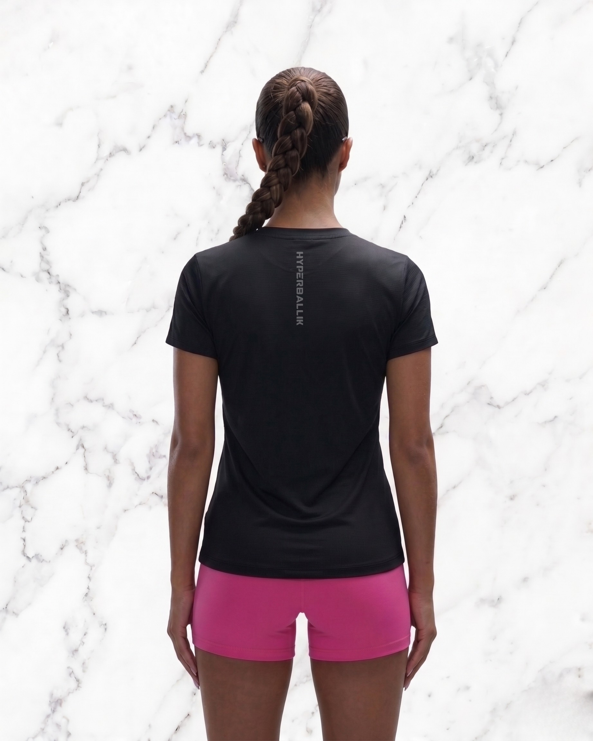 Person wearing a black t-shirt and pink shorts on a marble background