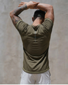 Person wearing an olive green athletic shirt and white pants against a neutral background
