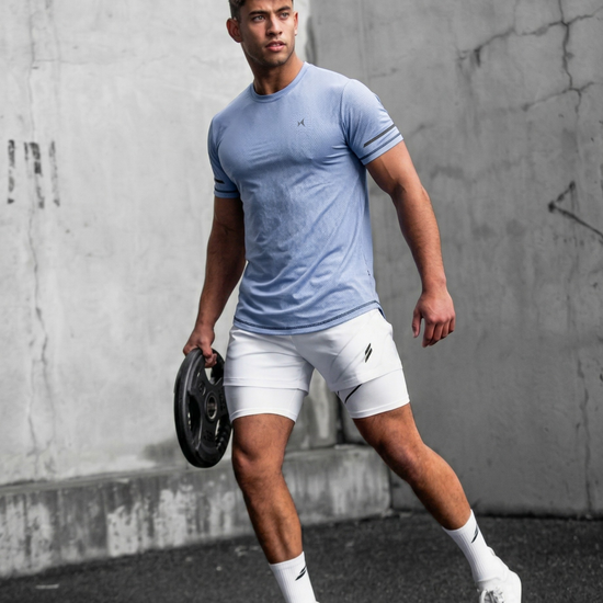Man in athletic wear holding a weight against a concrete wall.