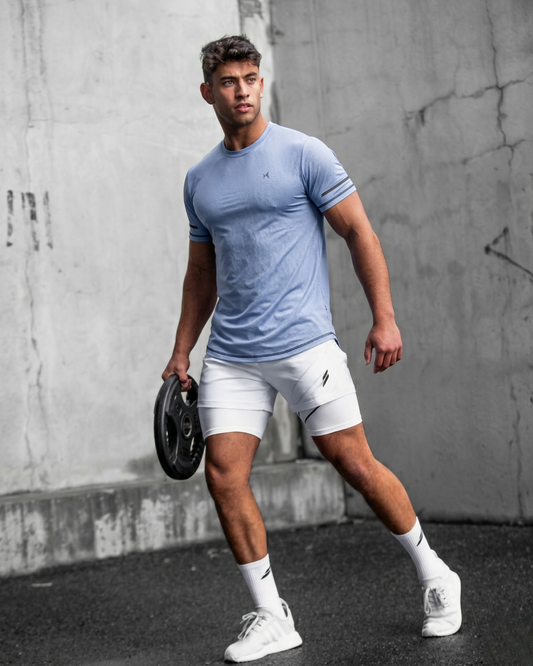 Man in athletic wear holding a weight against a concrete wall.
