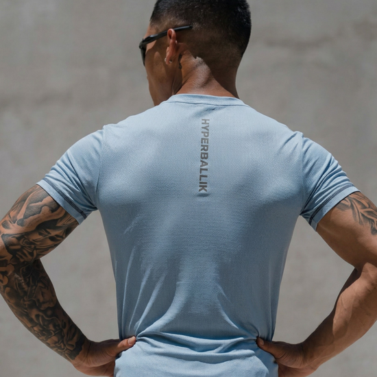 Man wearing a light blue t-shirt with 'Kanebali' branding, standing against a neutral background.