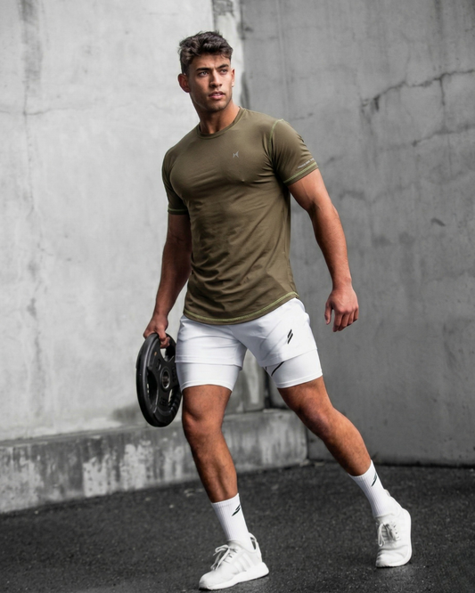 Man in athletic wear holding a weight against a concrete wall.