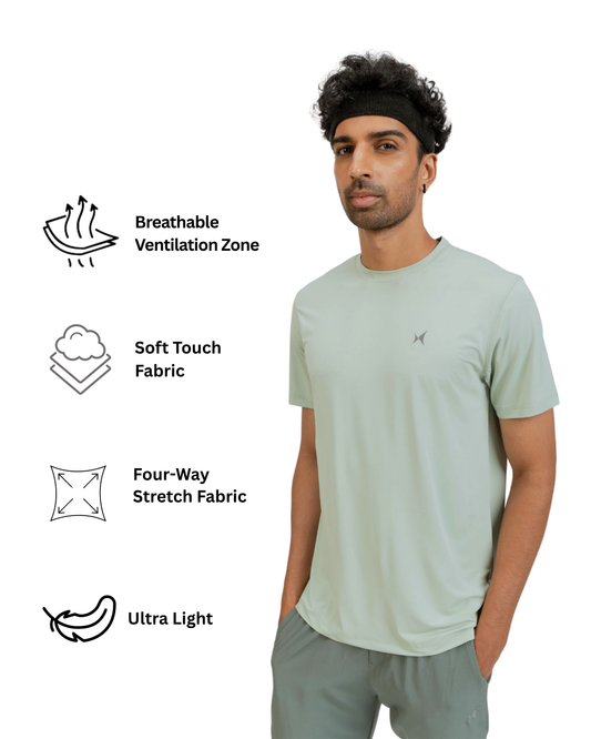 Man wearing a light green t-shirt with text and icons about fabric properties on a white background