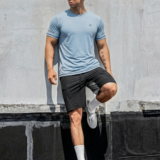 Man in athletic wear posing against a concrete wall