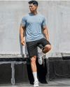 Man in athletic wear posing against a concrete wall