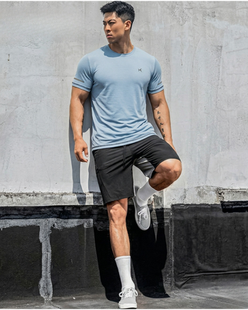 Man in athletic wear posing against a concrete wall