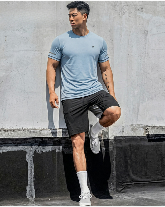 Man in athletic wear posing against a concrete wall