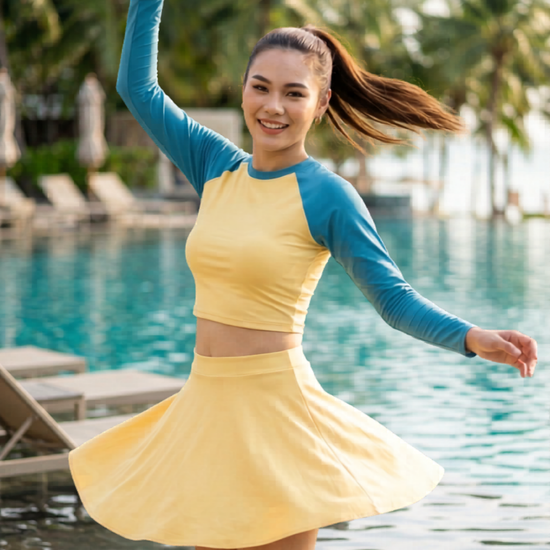 Woman wearing a yellow dress with blue sleeves on a gray background
