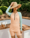 Woman wearing a peach and teal long-sleeve rash guard and shorts set outdoors.