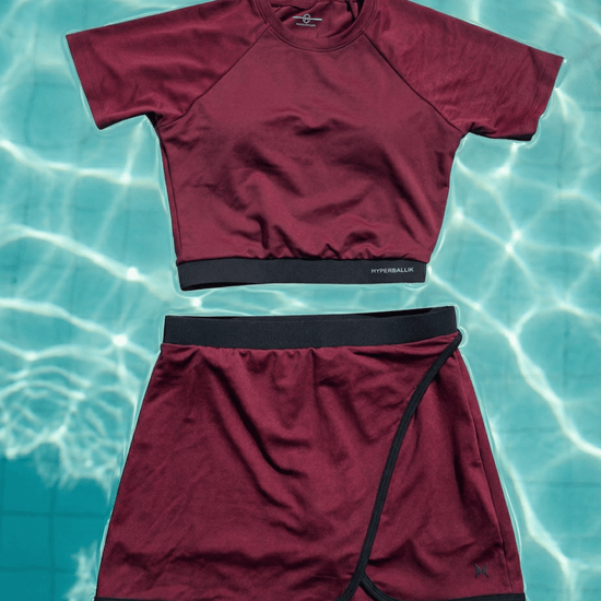 Maroon swim shirt and skirt set on a water background