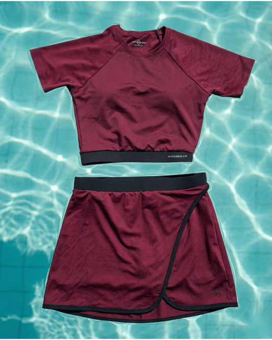 Maroon swim shirt and skirt set on a water background