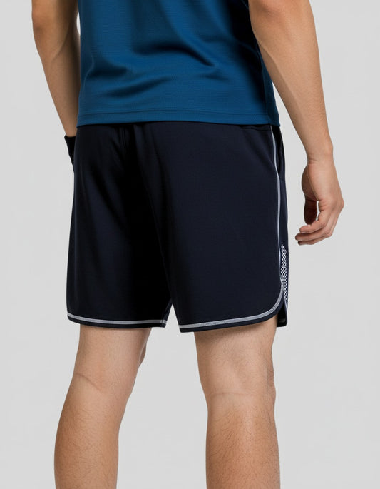 Person wearing navy shorts with white trim on a plain background