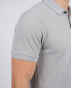 Close-up of the sleeve and bubble-knit fabric texture on a light grey polo shirt