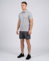 Man wearing a light grey textured bubble-knit polo shirt, three-quarter view on a pale grey studio background