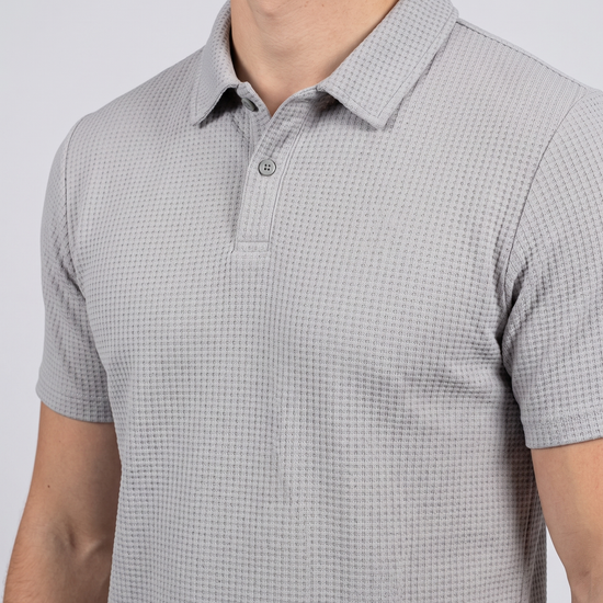 Close-up of the collar and placket on a light grey textured bubble-knit polo shirt